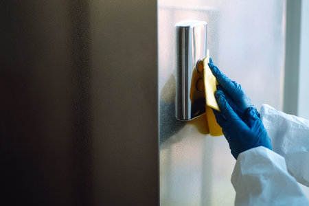 Man in Hazmat suit, protective gloves and goggles use sprayer equipment disinfect the entrance.の写真素材