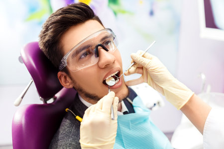 portrait of male. Dental Care Concept. Dental inspection is being given to Beautiful man surrounded by dentistの写真素材