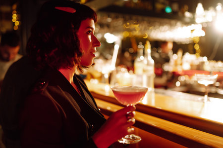 Gorgeous young superstar with cocktail disturbed by paparazzi in the night club (lounge bar).の写真素材