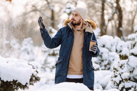 Portrait of young man in snowy winter forest. Season, christmas, travel and people concept.