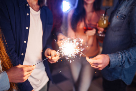 Group of friends having fun with sparklers. young people laugh. celebrating New Year together.の写真素材