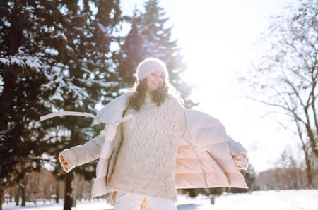 Happy woman in winter style clothes walking in the snowy park. Nature, holidays, travel concept.の写真素材