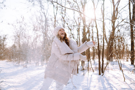 Young woman in winter style clothes walking in the snowy park. Winter fashion, holidays.