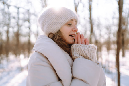 Young woman in winter style clothes walking in the snowy park. Winter fashion, holidays.
