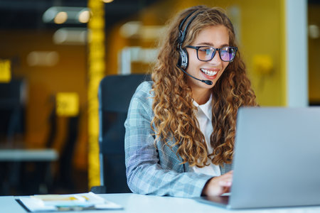 Call center agent with headset working on support hotline in modern office. video conference.の写真素材