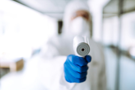 Disease control expert with an Infrared thermometer equipment to check the temperature at office.