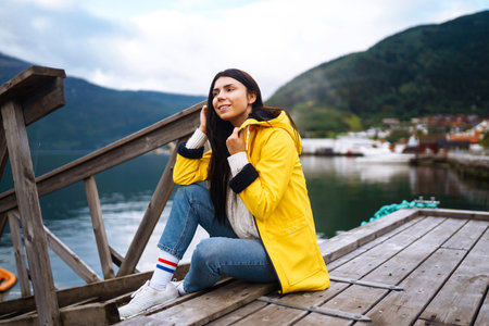 The girl tourist in a yellow jacket. Active woman relaxing in Norway. Traveling, lifestyle, adventure.の写真素材