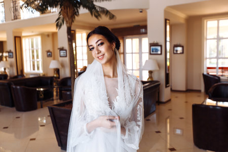 Beautiful bride in fashion wedding dress with a long luxury veil. The stunning young bride is incredibly happy.の写真素材