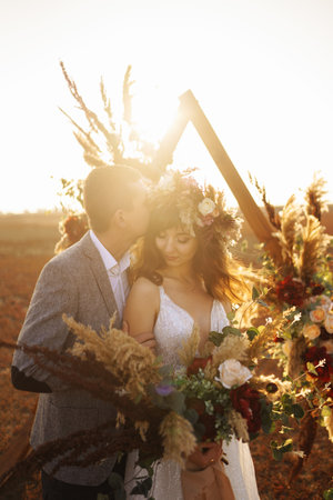 young and beautiful bride and groom enjoy each other. Wedding day in boho style. warm summertime.の写真素材