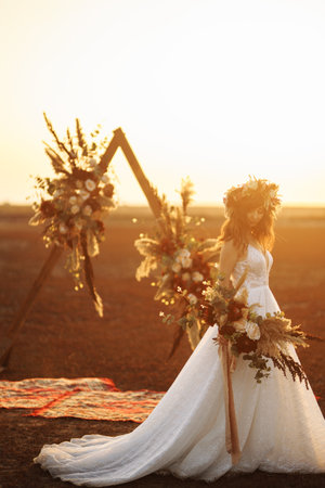 Amazing bride in sunset light. Pretty bride. boho style. Bride wearing fashion wedding dress with feathers.の写真素材