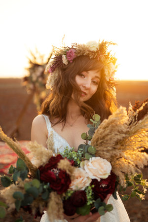 Amazing bride in sunset light. Pretty bride. boho style. Bride wearing fashion wedding dress with feathers.の写真素材