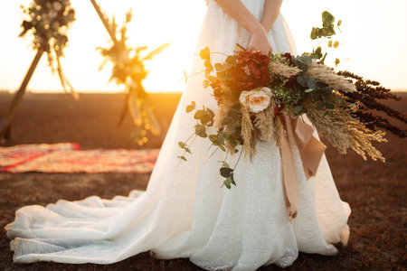 Amazing bride in sunset light. Pretty bride. boho style. Bride wearing fashion wedding dress with feathers.の写真素材