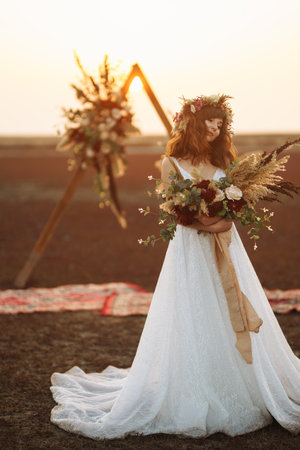 Amazing bride in sunset light. Pretty bride. boho style. Bride wearing fashion wedding dress with feathers.の写真素材
