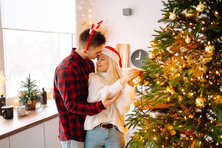 Happy couple decorating christmas tree at home. Smiling Man and Woman together Celebrating Christmasの写真素材