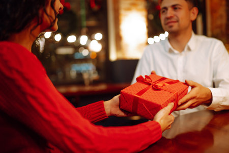 Exchange of gifts. Man gives to his woman surprise a gift box with red ribbon. romantic day.の写真素材