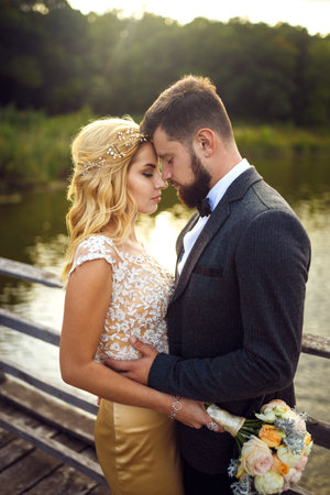 Stylish couple of happy newlyweds posing in the park on their wedding day.. Sexy kissing stylish couple.の写真素材