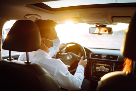 Man driving a car wearing on a medical mask during an epidemic, a driver- taxi in a mask. Covid-2019の素材 [FY310195062379]