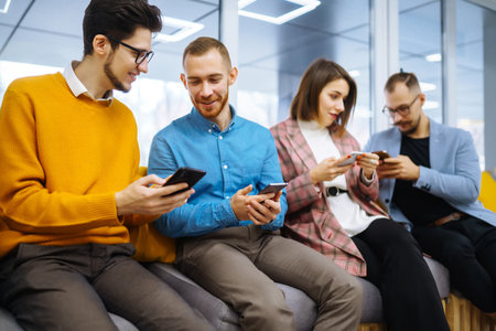 Group of young people using mobile phone. Business colegios sitting side by side in a modern office.