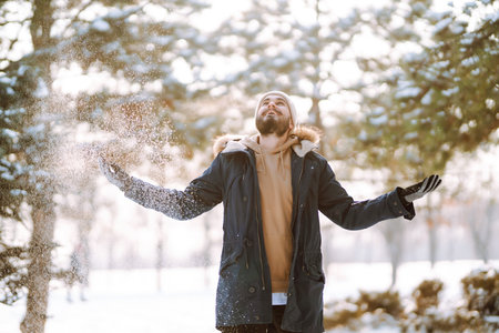 Portrait of young man in snowy winter forest. Season, christmas, travel and people concept.