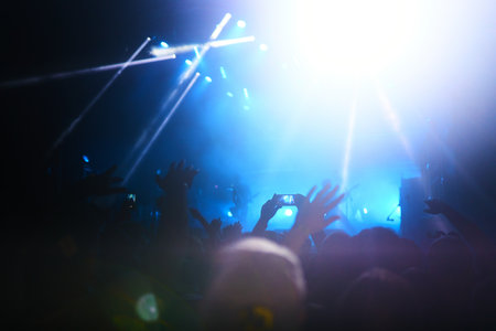 Hand with a phone records live music festival. People taking photographs with smart phone during...