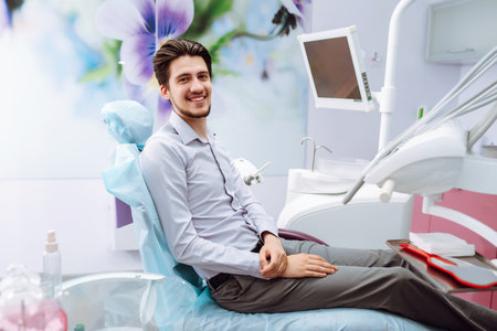 Young man at the dentist's chair during a dental procedure. Overview of dental caries prevention.の写真素材