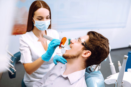 Young man at the dentist's chair during a dental procedure. Overview of dental caries prevention.の写真素材