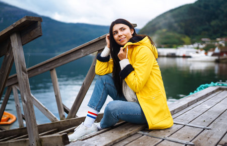 Girl tourist in yellow jacket. Active woman relaxing in Norway. Traveling, lifestyle, adventure.