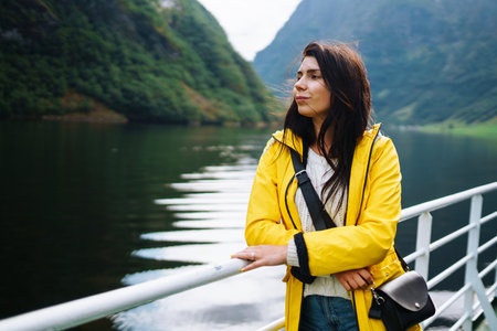 Girl tourist on a pleasure boat on the fjord enjoys the picturesque mountains and lakes of Norway.の写真素材