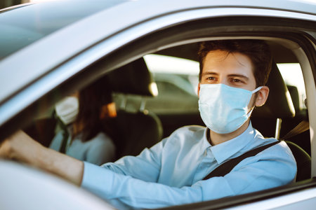Man driving a car wearing on a medical mask during an epidemic, a driver- taxi in a mask. Covid-2019の写真素材