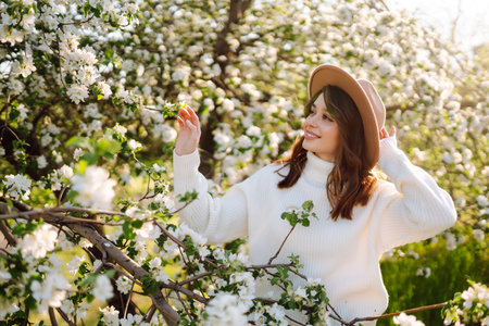 Smiling woman with hat posing in blooming spring park. The concept of relax, travel. fashion style.