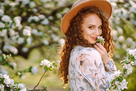 Smiling woman with hat in spring park. The concept of relax, travel, freedom.