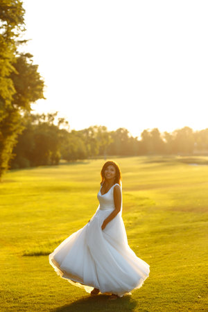 Happy beautiful young bride outside on a summer meadow at the sunset. . wedding day.の写真素材