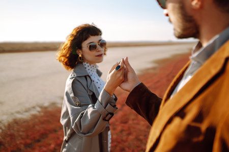 Stylish couple enjoying autumn weather in autumn field. Lovely couple walking in the field together.