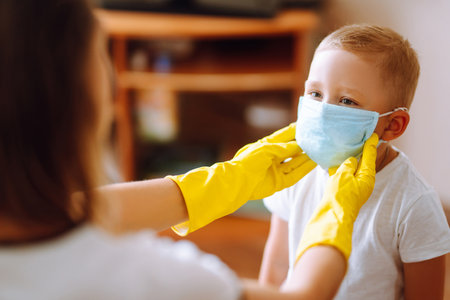 Little boy and mom in medical mask. Mother puts on her baby sterile medical mask. Wearing face mask.の写真素材