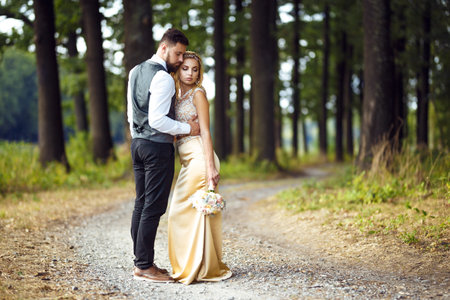 Stylish couple of happy newlyweds posing in the park on their wedding day. Perfect couple bride.の写真素材