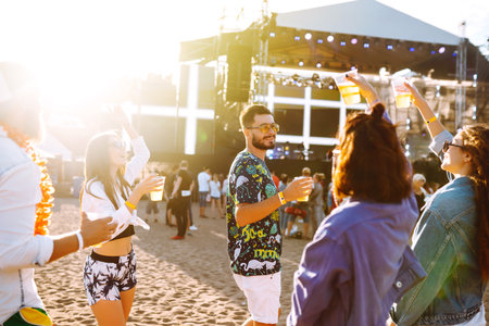 Group of friends with beer dancing and having fun at music festival together. summer beach party.