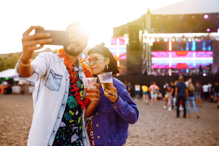 Young and cheerful couple at music festival. Happy friends drinking beer and having fun.