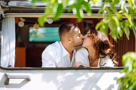 Beautiful wedding couple laugh and kiss relaxing in rv, camping in a trailer. romantic moment.の写真素材