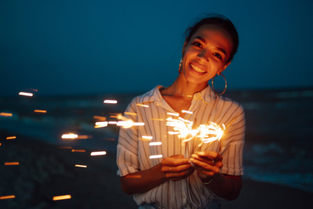 Glowing sparkles in hands. Women with Christmas sparklers on nature and twill light sky background.の写真素材