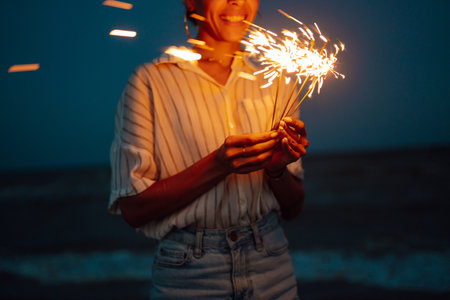 Glowing sparkles in hands. Women with Christmas sparklers on nature and twill light sky background.の写真素材