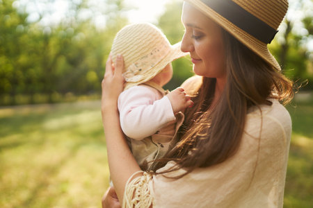 Happy harmonious family outdoors dressed in cool hats. mother with her baby have fan. summer evening