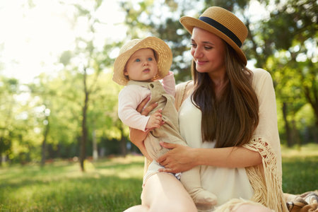 Happy harmonious family outdoors dressed in cool hats. mother with her baby have fan. summer eveningの写真素材