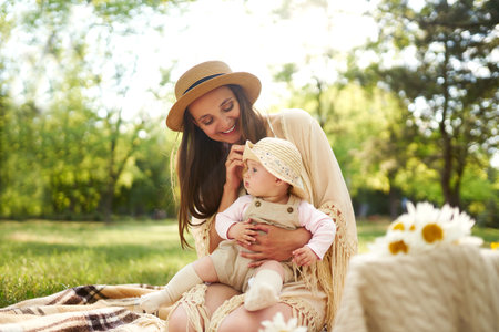 Happy harmonious family outdoors dressed in cool hats. mother with her baby have fan. summer eveningの写真素材