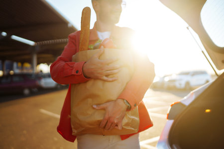 Young man with shopping bag full of vegetables near the car. Handsome man after shopping.の写真素材