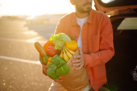 Young man with shopping bag full of vegetables near the car. healthy lifestyle.の写真素材