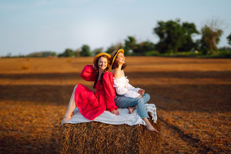 Two young women having fun near haystack. fashion concept. summer concept.の写真素材