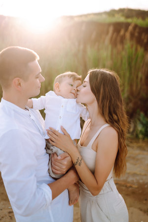 Cheerful young family with little baby boy spending time together on the beach.
