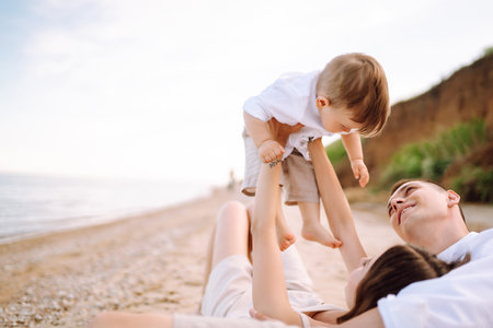 Cheerful young family with little baby boy spending time together on the beach.の写真素材