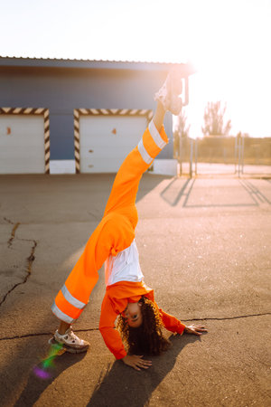 Young African American woman - dancer dancing in the street at sunset. Stylish woman with curly hair...