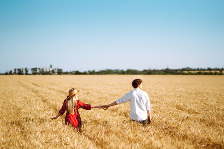 Young happy couple hugging on a wheat field, on the sunset. enjoying time together.の写真素材